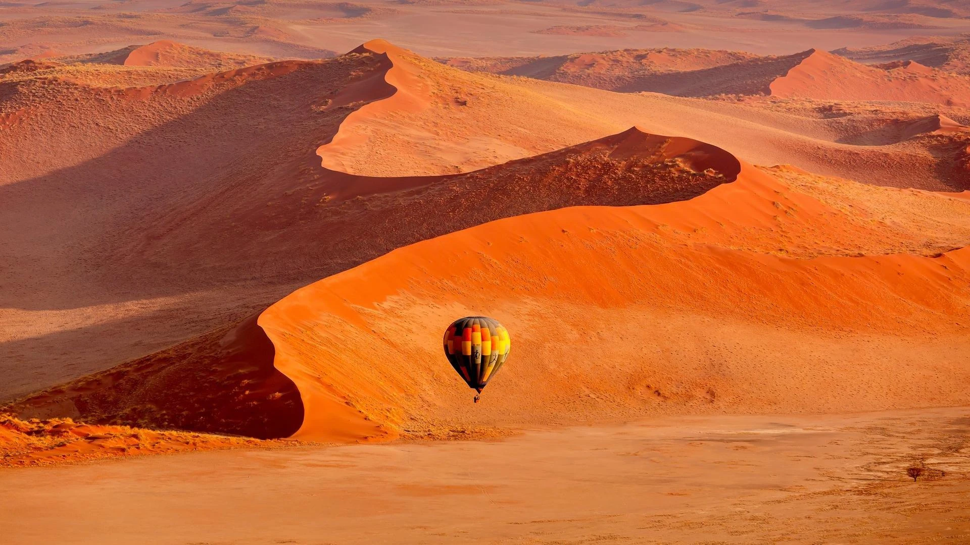A hot-air balloon above the sculpted orange dunes of the Namib Desert