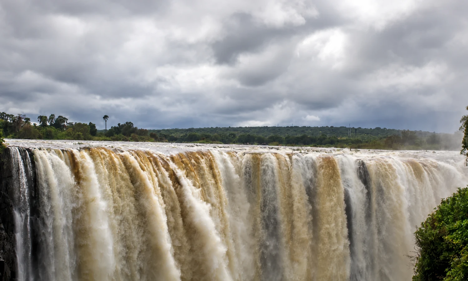 Victoria Falls cascading into a misty gorge beneath a cloudy sky