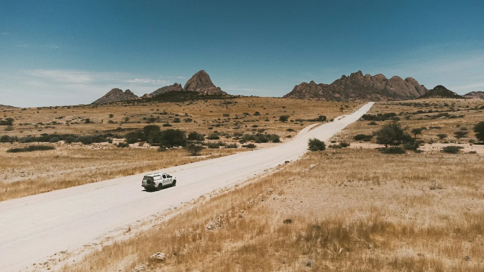 A vehicle travelling on an open desert road near Spitzkoppe