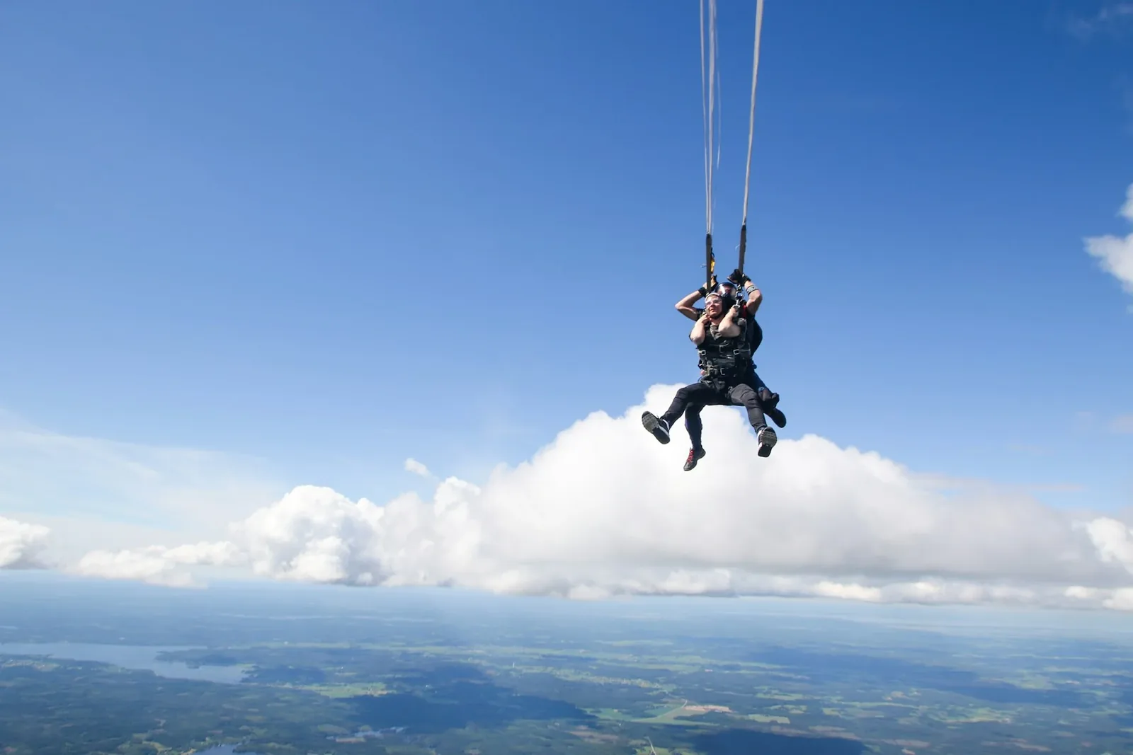 Two skydivers flying tandem beneath a blue sky
